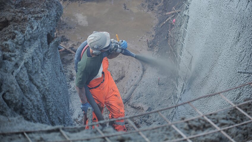 The cement mixture is pumped through a hose and then pneumatically sprayed onto a surface.