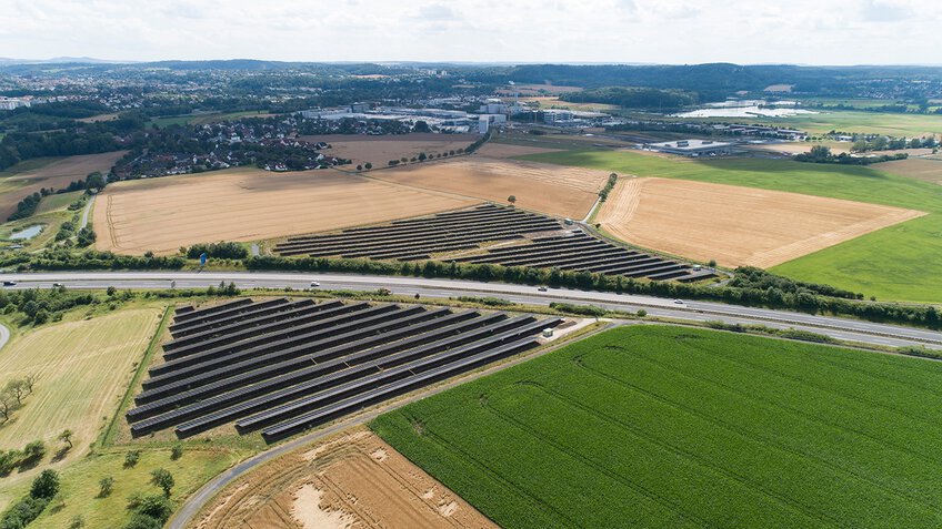 Großer Photovoltaik-Park in grüner Hügellandschaft – Symbol für den Einsatz für klimafreundliche Energie und nachhaltige Druckluftversorgung.